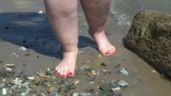 Fat bare legs with red pedicure walk along the bank of the river, fetish.